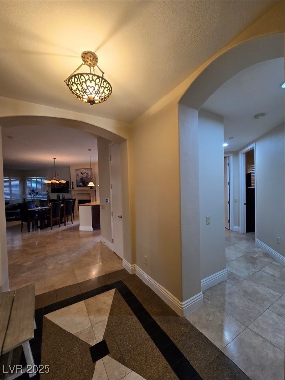 20 Via Mantova, Unit 202 Henderson, NV 89011 - Photo 26 of 60 Corridor featuring arched walkways, inlaid floor details, a chandelier, and recessed lighting
