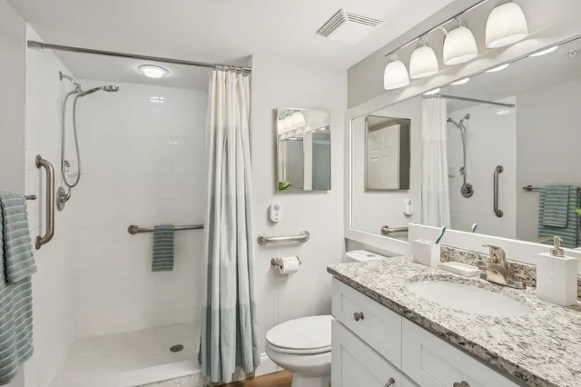 a bathroom with a granite countertop sink toilet and shower glass cabinet