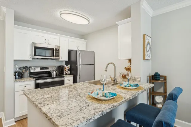 a kitchen with stainless steel appliances granite countertop a table chairs and a refrigerator