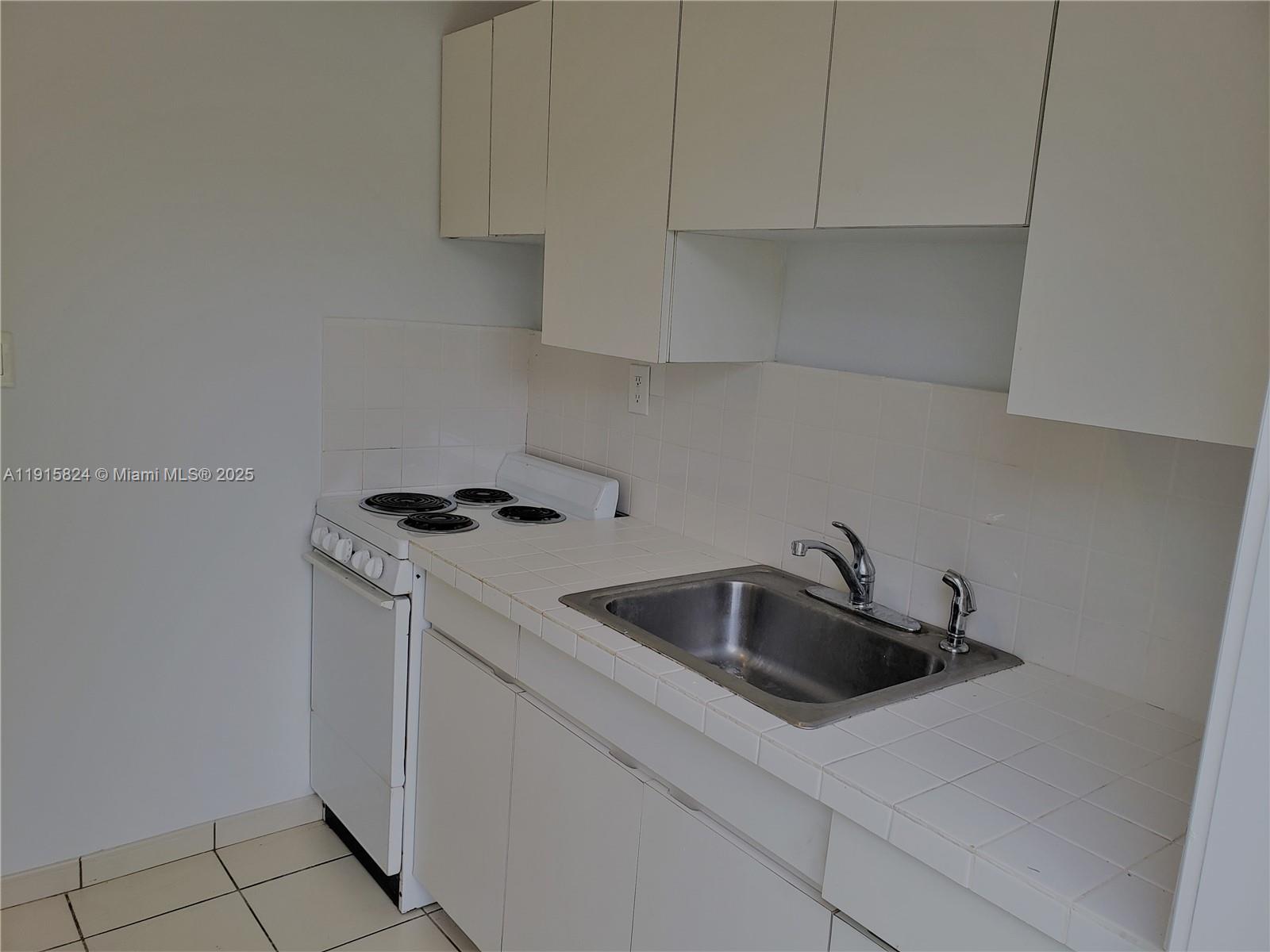 2140 Southwest 25th Street, Unit A Miami, FL 33133 - Photo 8 of 8 a kitchen with white cabinets and a sink