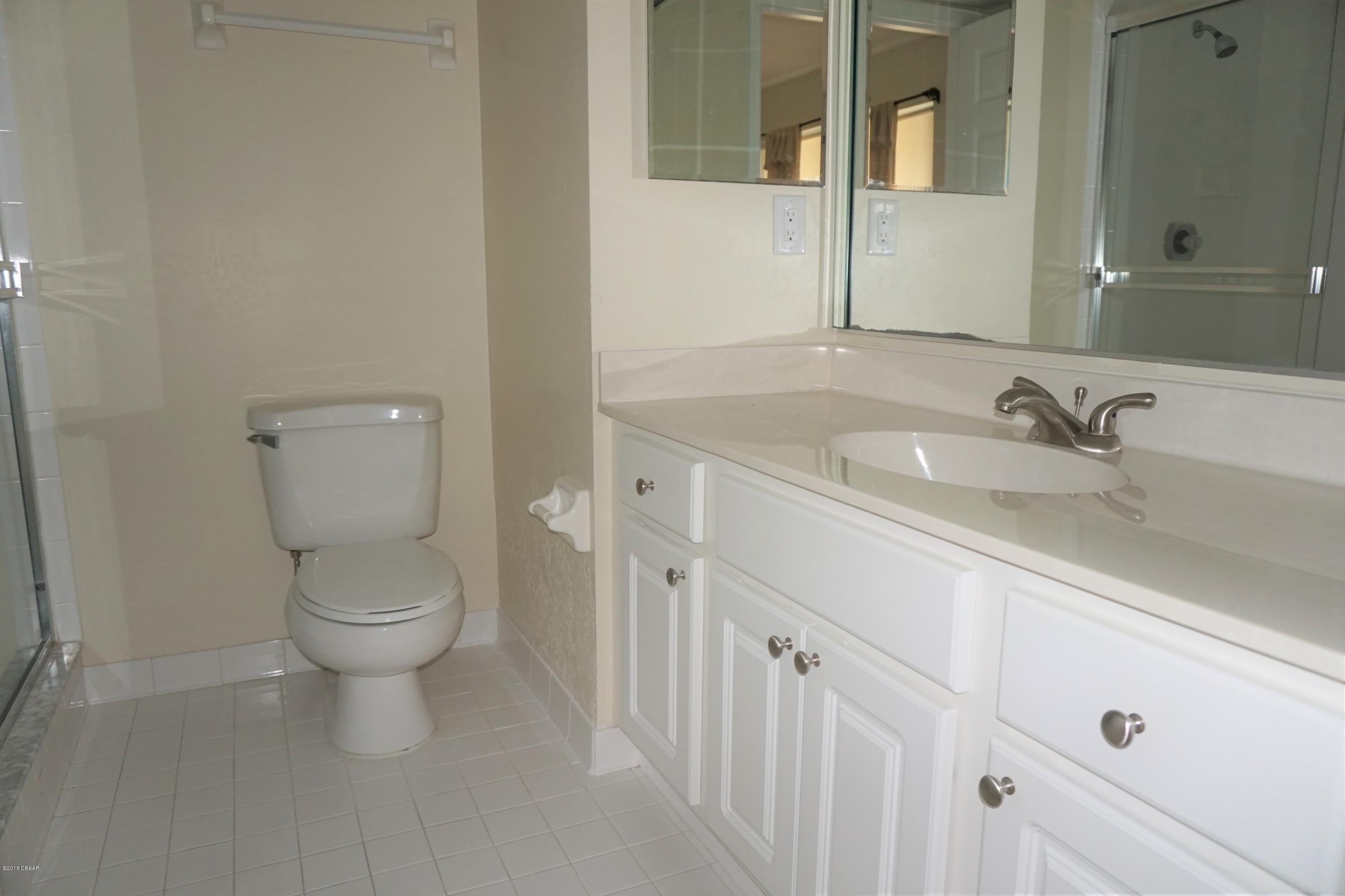 1 John Anderson Drive, Unit 113 Ormond Beach, FL 32176 - Photo 30 of 76 a bathroom with a toilet a sink and mirror