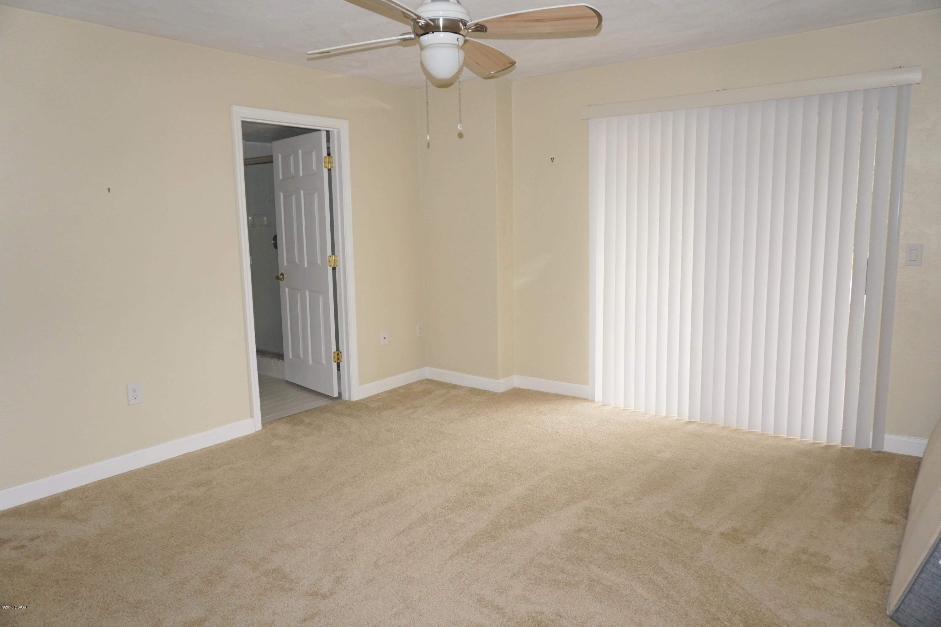 1 John Anderson Drive, Unit 113 Ormond Beach, FL 32176 - Photo 32 of 76 an empty room with a ceiling fan and a window