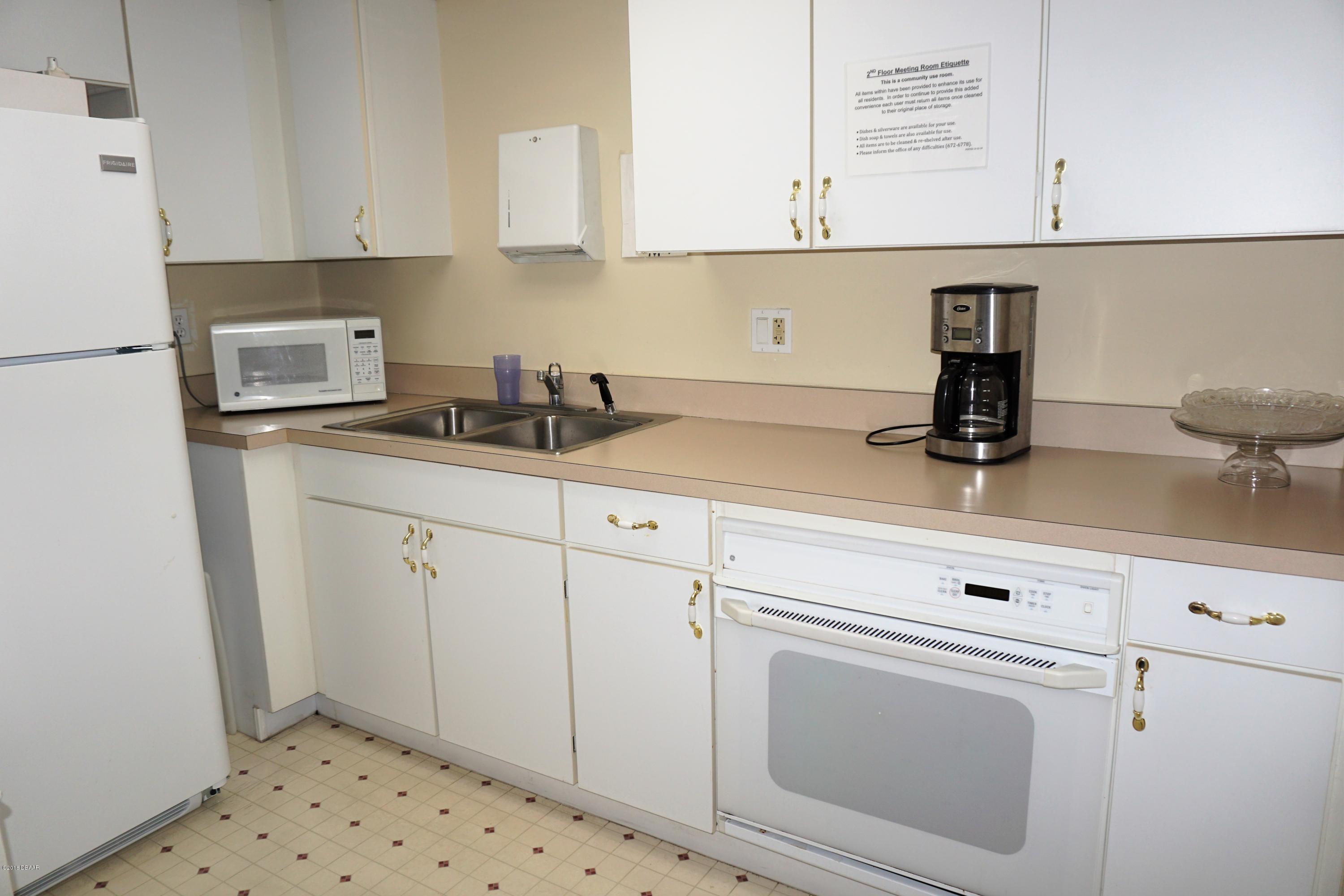 1 John Anderson Drive, Unit 113 Ormond Beach, FL 32176 - Photo 56 of 76 a kitchen with granite countertop white cabinets and white appliances