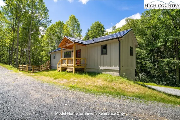 a front view of house with yard and trees in the background