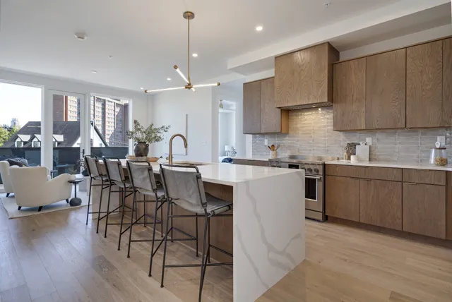 a large kitchen with cabinets chairs and wooden floor