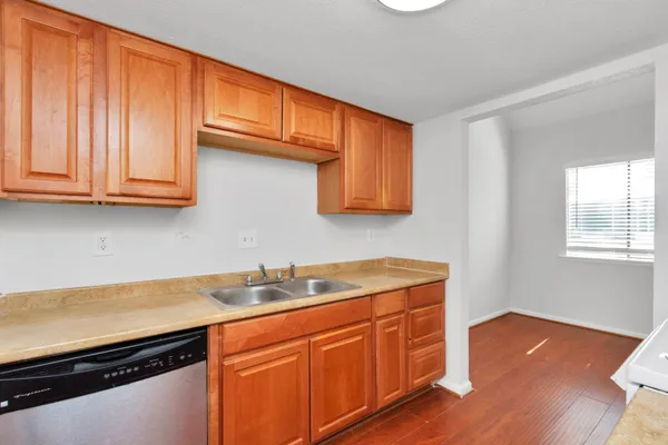 a kitchen with stainless steel appliances granite countertop wooden cabinets a sink and dishwasher with wooden floor