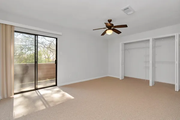 an empty room with a chandelier fan and windows