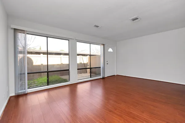 a view of an empty room with wooden floor and a window