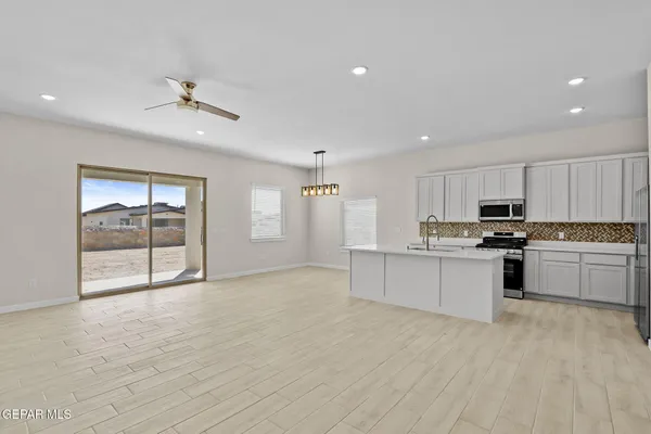 a large white kitchen with kitchen island a sink stainless steel appliances and cabinets