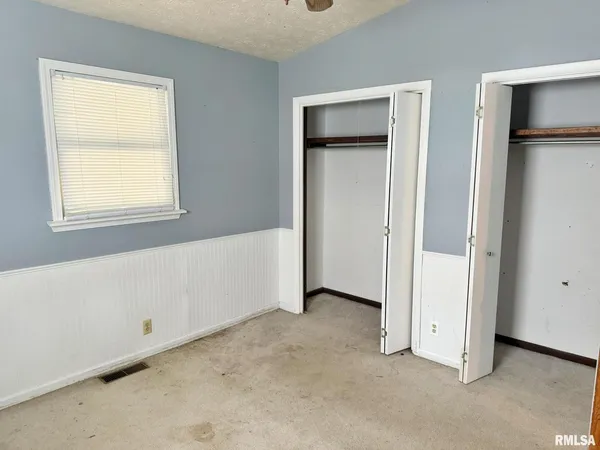 a view of an empty room with closet and a window