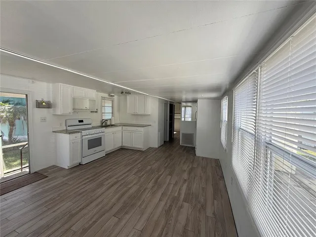 a kitchen with white cabinets and wooden floor