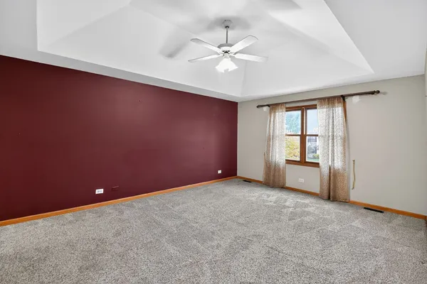 an empty room with chandelier fan and windows