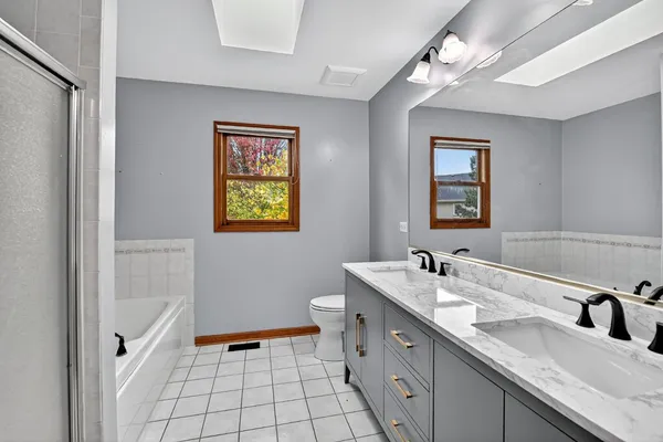 a spacious bathroom with a double vanity sink mirror and bathtub
