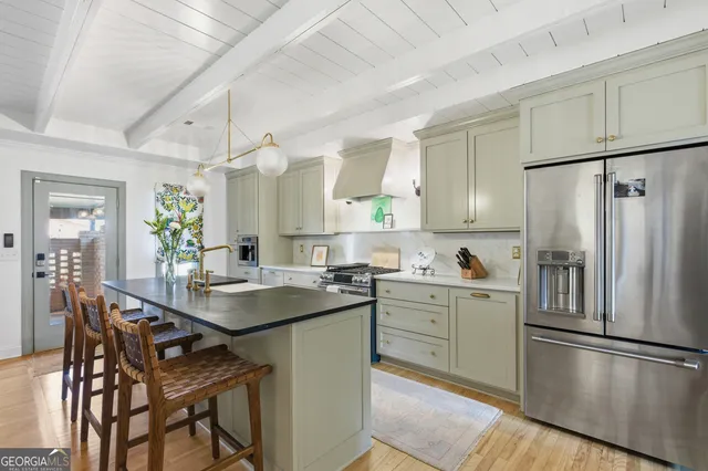 a kitchen with stainless steel appliances granite countertop a refrigerator a sink a stove a dining table and chairs