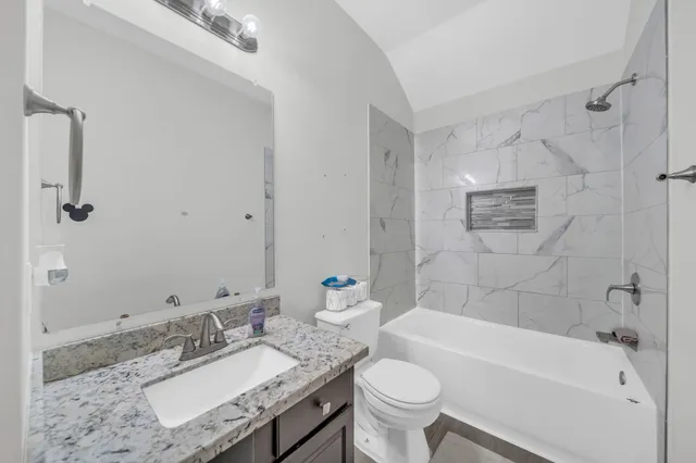 a bathroom with a granite countertop sink mirror toilet and bathtub