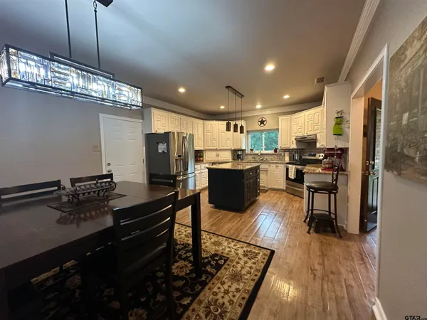 a kitchen with stainless steel appliances kitchen island granite countertop a stove refrigerator and cabinets