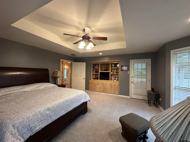 a spacious bedroom with a large bed couch and windows