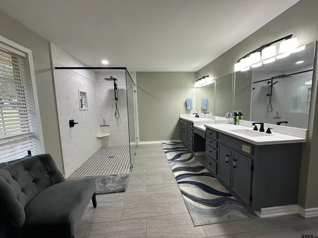 a spacious bathroom with a double vanity sink a large mirror and shower