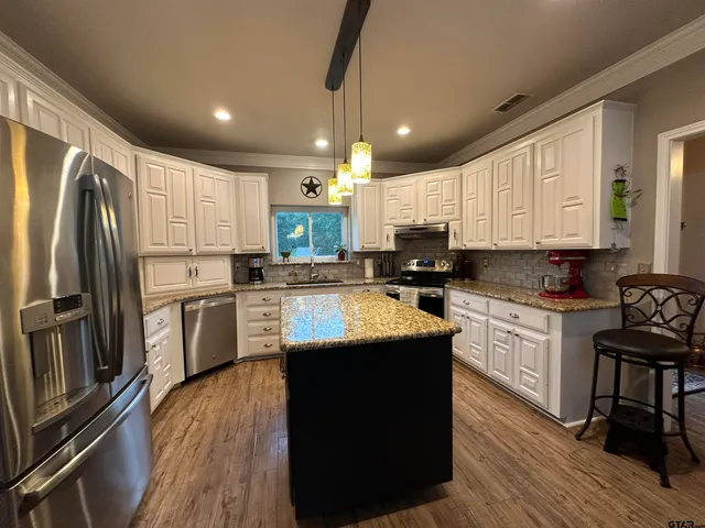 a kitchen with kitchen island granite countertop a sink cabinets and stainless steel appliances