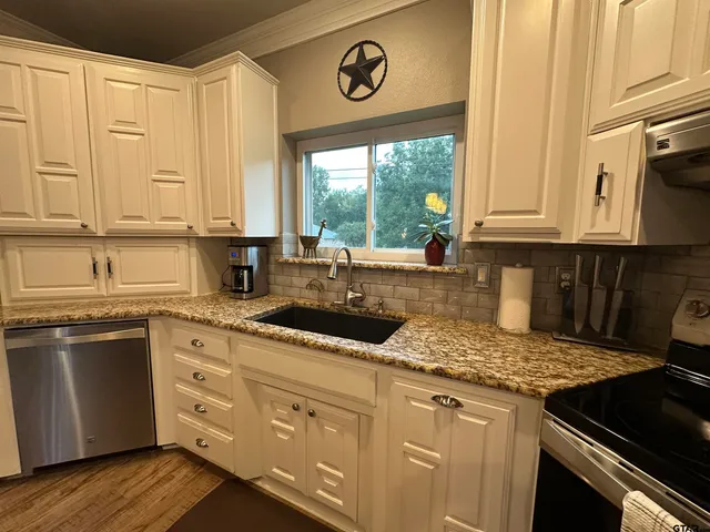 a kitchen with granite countertop a sink stove and cabinets