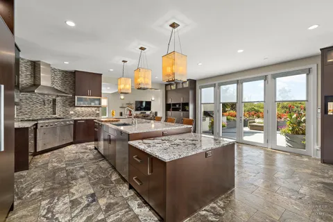 a large kitchen with kitchen island a large counter top stainless steel appliances and cabinets
