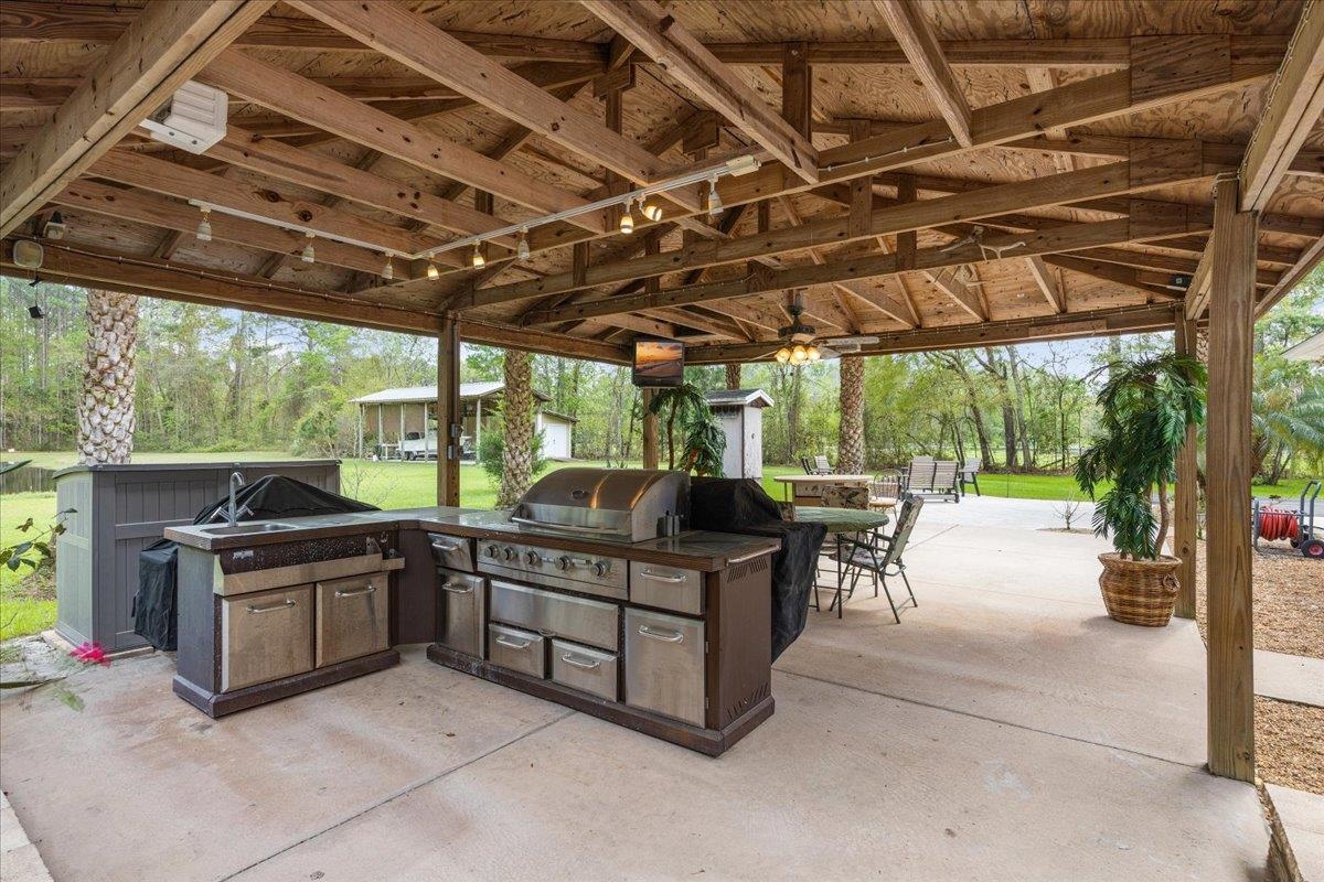 3180 B Pacetti Road St. Augustine, FL 32092 - Photo 23 of 42 a view of a patio with table and chairs under an umbrella with a big yard