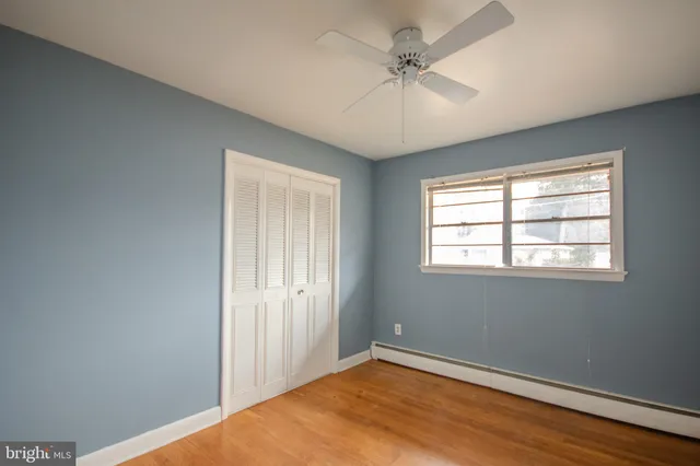 an empty room with a chandelier fan and windows