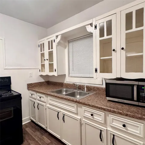 a kitchen with granite countertop white cabinets and black appliances