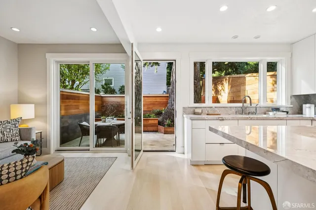 a open kitchen with granite countertop a refrigerator a sink and white cabinets with wooden floor