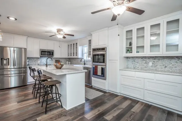 a kitchen with stainless steel appliances a dining table chairs and refrigerator