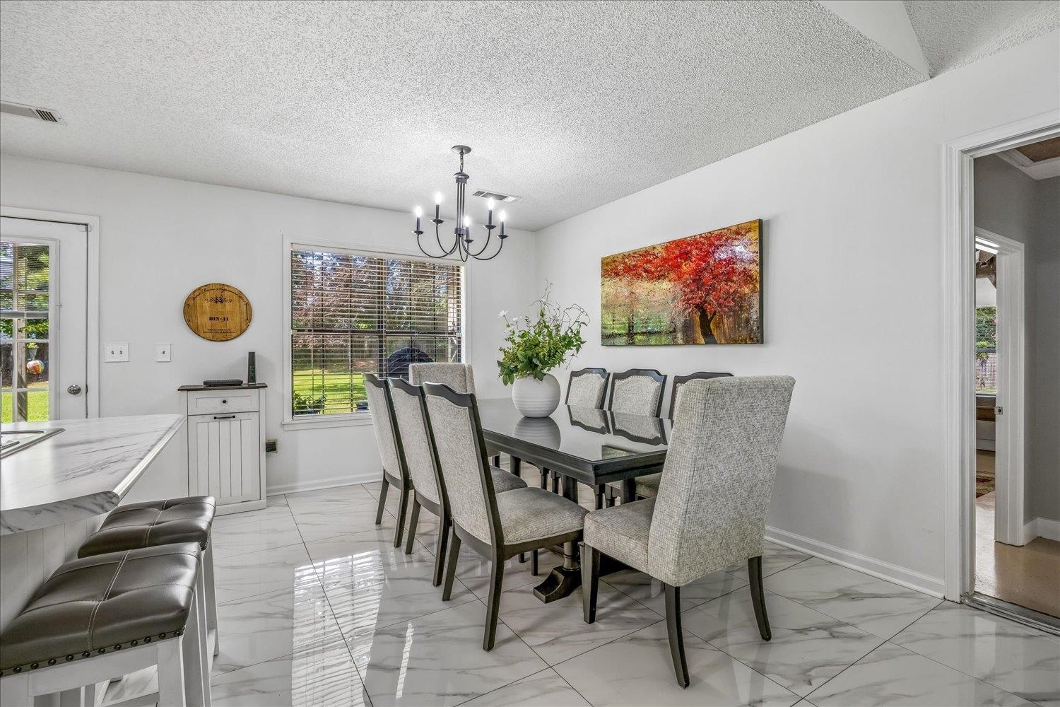 184 Cherokee Road Millington, TN 38053 - Photo 5 of 27 Dining area featuring a contemporary chandelier, large window with outdoor views, light-toned walls, and marble-look tile flooring