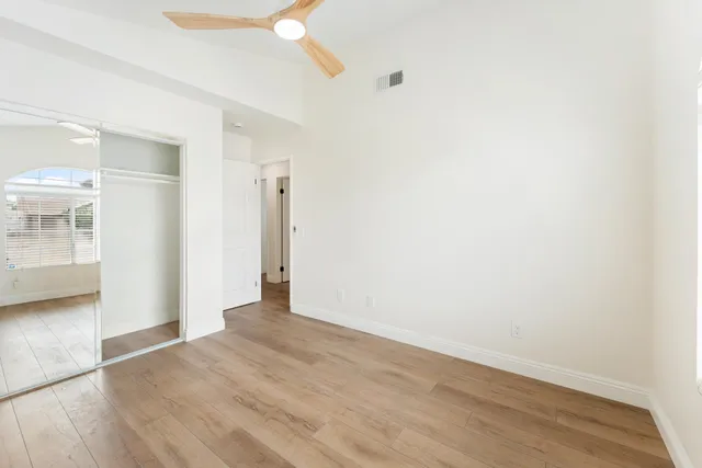 a view of empty room with wooden floor and fan