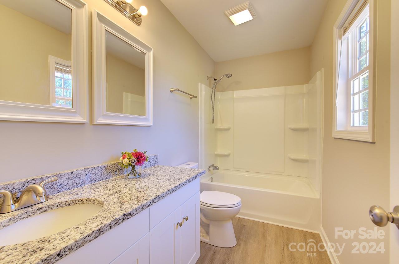 6130 Hopewell Road Hickory Grove, SC 29717 - Photo 13 of 29 a bathroom with a granite countertop sink mirror vanity bathtub and toilet
