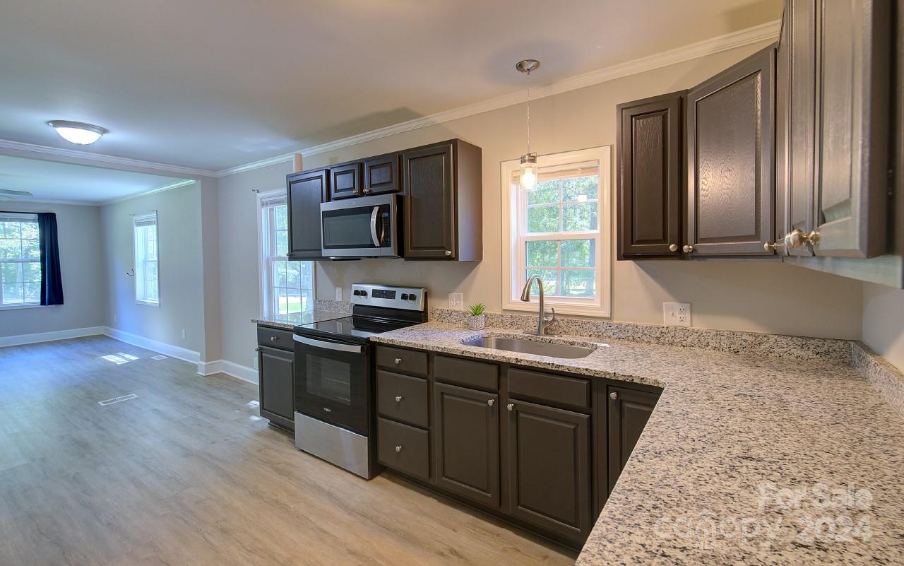 6130 Hopewell Road Hickory Grove, SC 29717 - Photo 8 of 29 a kitchen with stainless steel appliances granite countertop a sink stove and wooden cabinets