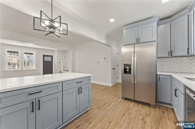 a kitchen with stainless steel appliances granite countertop a refrigerator a sink dishwasher a kitchen island with wooden floor and cabinets