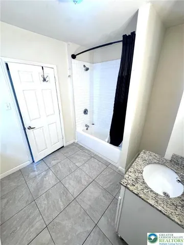 a bathroom with a granite countertop sink a mirror and shower