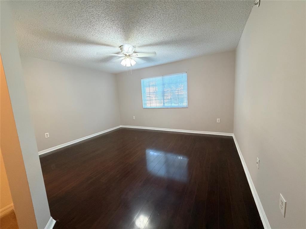 5025 Wiles Road, Unit 101 Coconut Creek, FL 33073 - Photo 11 of 27 an empty room with wooden floor chandelier fan and windows