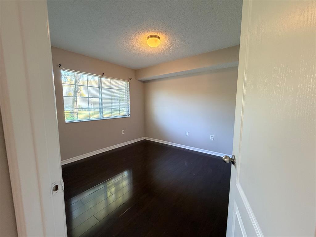 5025 Wiles Road, Unit 101 Coconut Creek, FL 33073 - Photo 20 of 27 an empty room with wooden floor and windows
