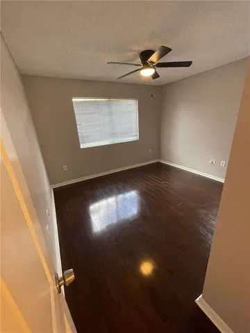 a view of an empty room with wooden floor and windows