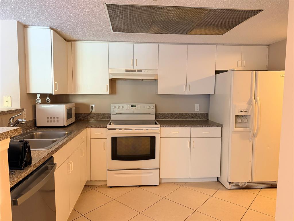 5025 Wiles Road, Unit 101 Coconut Creek, FL 33073 - Photo 7 of 27 a kitchen with stainless steel appliances granite countertop a refrigerator sink and white cabinets