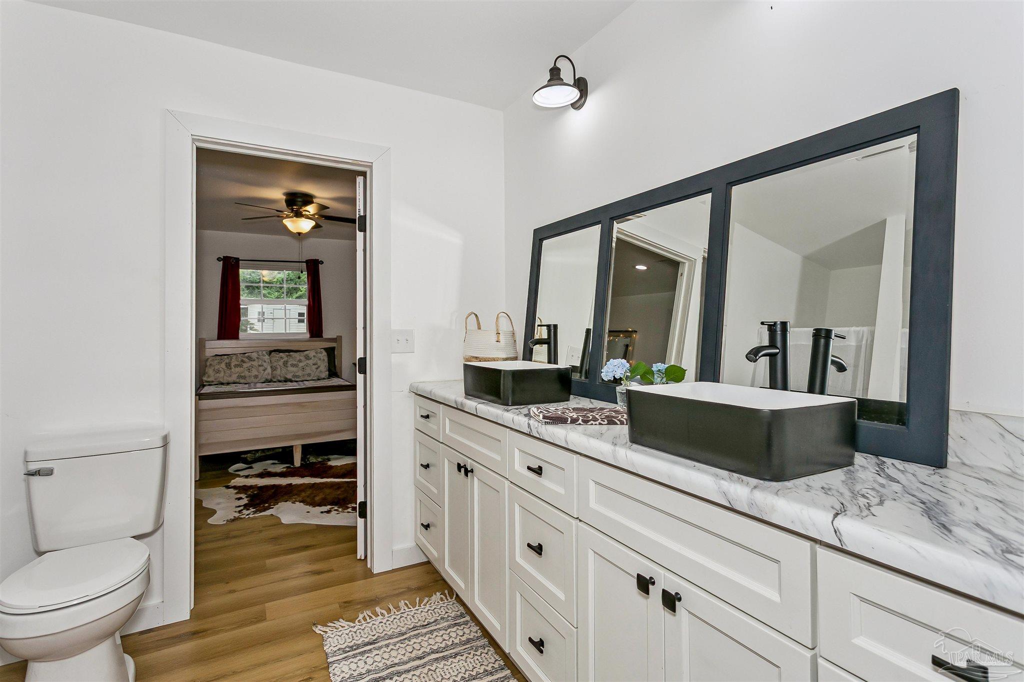 1095 River Annex Road Cantonment, FL 32533 - Photo 18 of 32 a spacious en suite bathroom with a granite countertop toilet a sink and a mirror