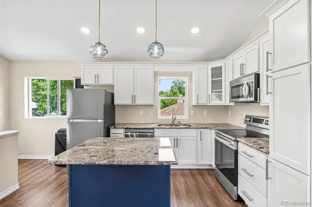 a kitchen with stainless steel appliances kitchen island wooden floors and view living room
