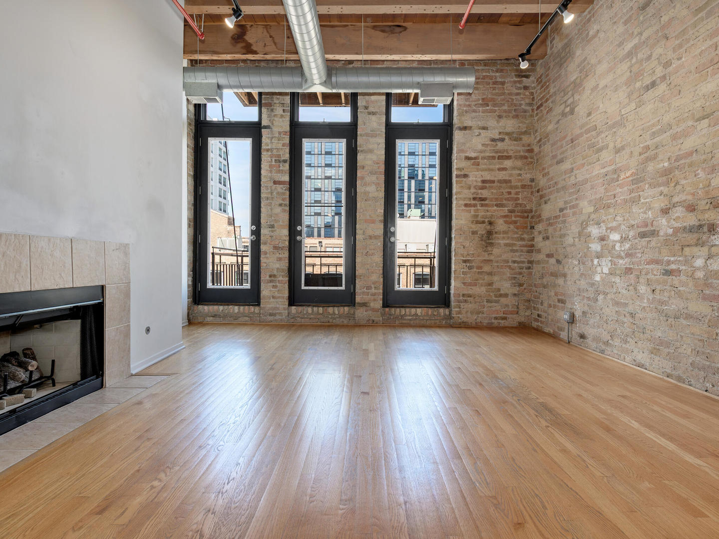 375 West Erie Street, Unit 508 Chicago, IL 60654 - Photo 6 of 16 an empty room with wooden floor fireplace and windows