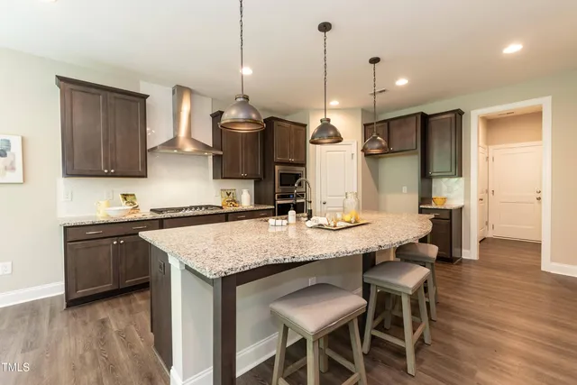 a kitchen with stainless steel appliances granite countertop a kitchen island a stove a table and chairs