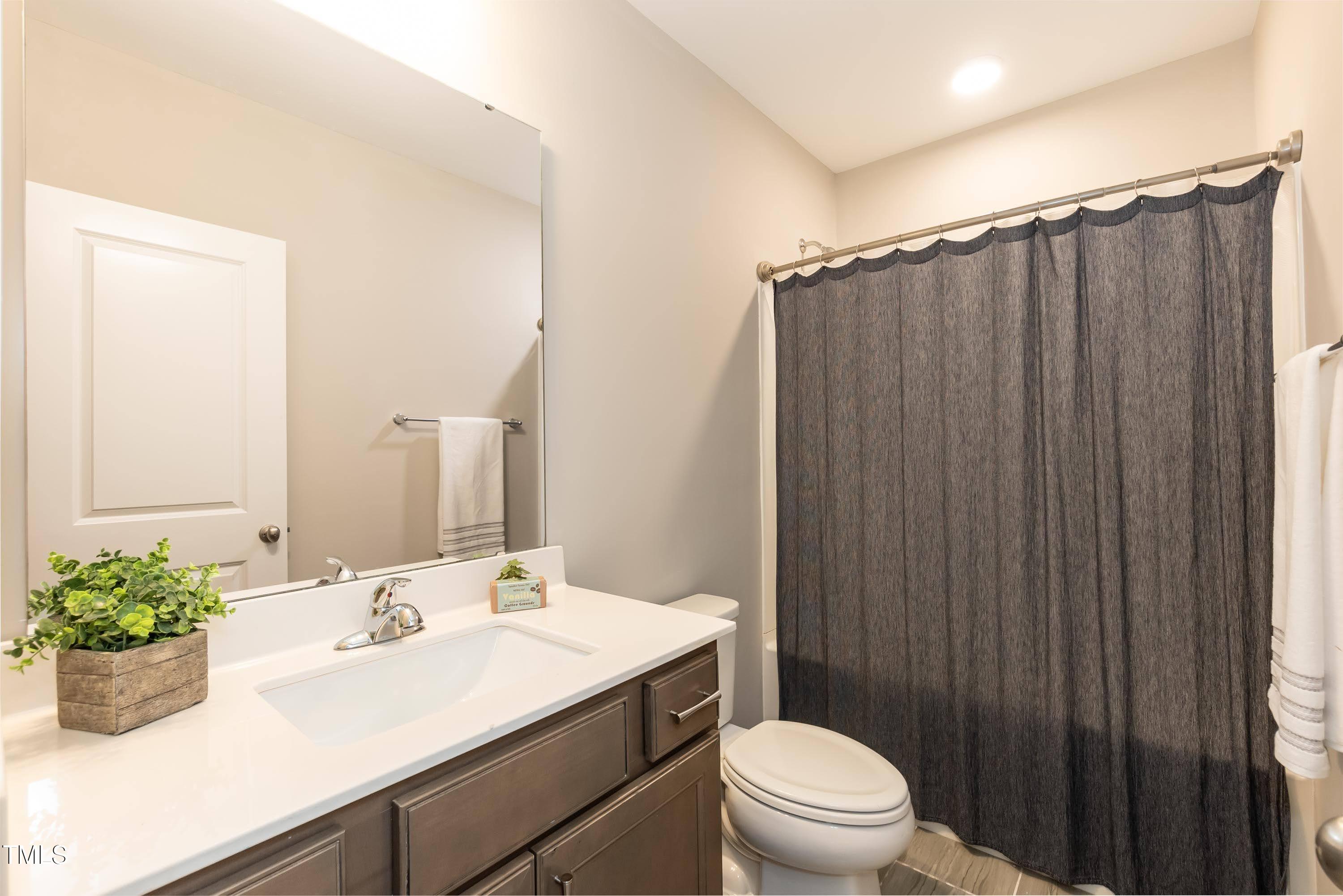 273 Scarlet Tanager Circle Holly Springs, NC 27540 - Photo 22 of 35 a bathroom with a sink a toilet a mirror and vanity