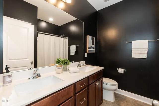 a bathroom with a double vanity sink toilet and a mirror