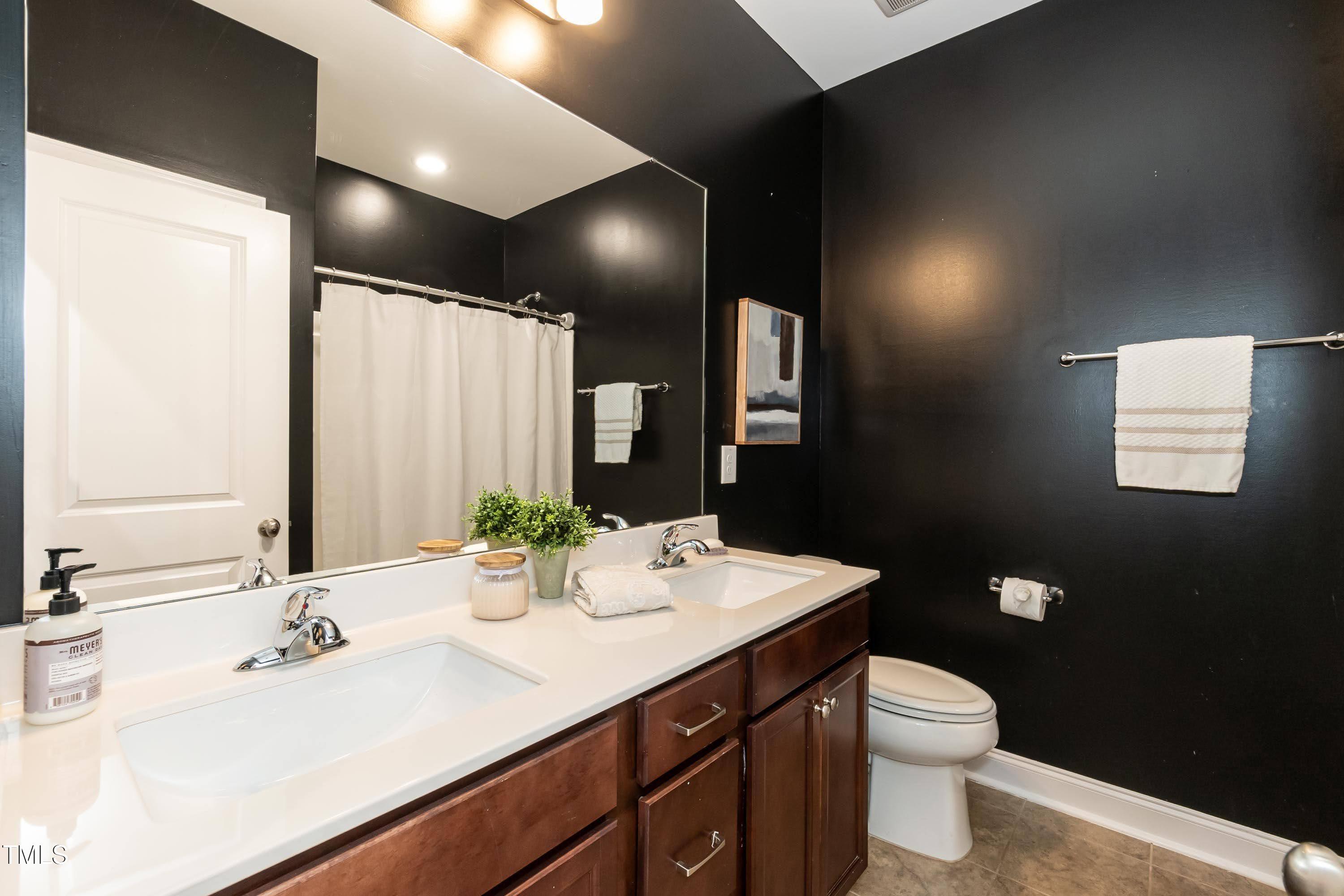 273 Scarlet Tanager Circle Holly Springs, NC 27540 - Photo 24 of 35 a bathroom with a double vanity sink toilet and a mirror