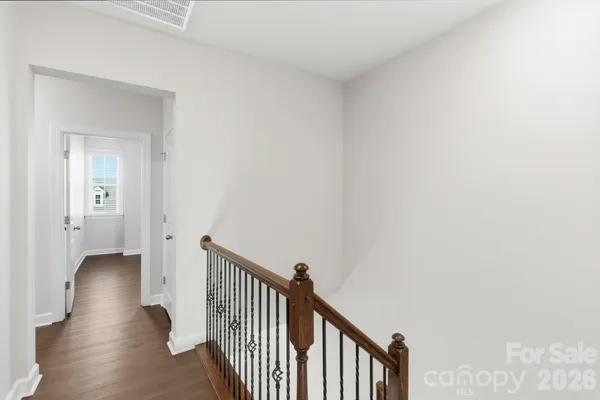 an empty room with wooden floor chandelier fan and windows