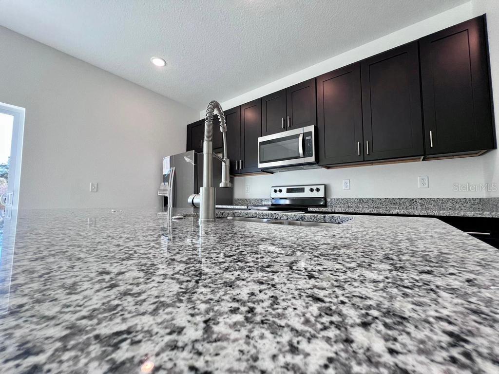 6325 Southwest 144th Lane Road Ocala, FL 34473 - Photo 7 of 31 a kitchen with kitchen island a stove a sink and a microwave