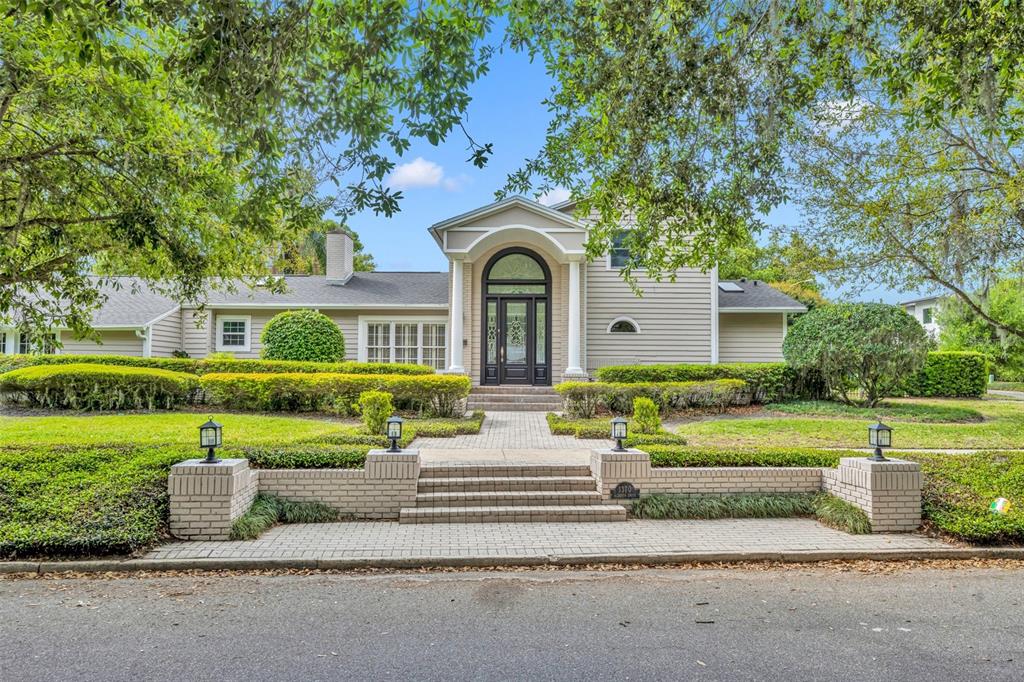 a front view of a house with garden and trees